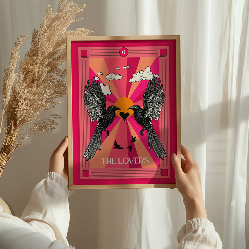 A person holding a framed art print of the lovers tarot card featuring two birds