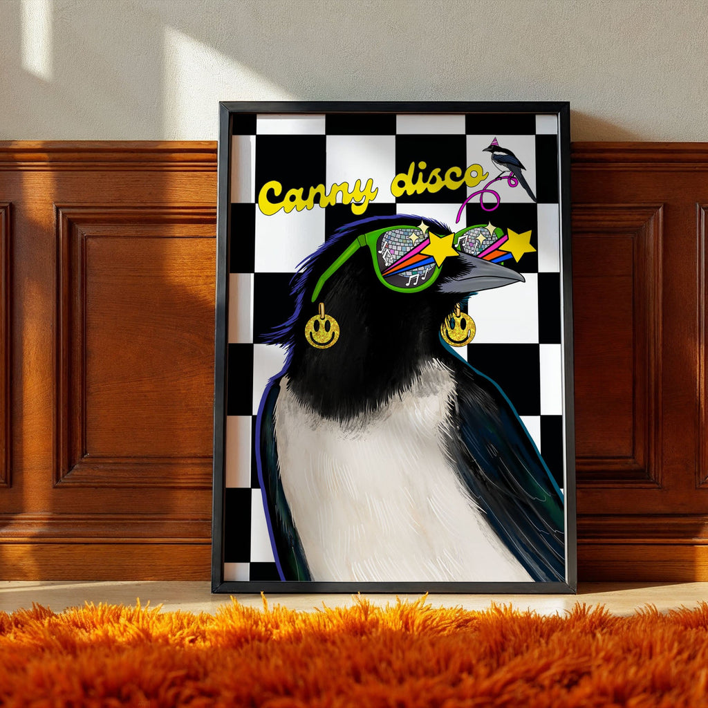 A framed print of a two magpies with words "canny Disco" featuring illustrations of magpies, disco balls smiley faces, and stars on a checkered black and white background representing Newcastle Geordies