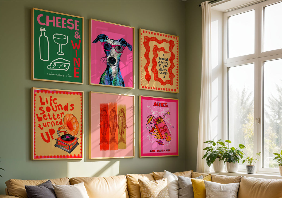 Colourful gallery wall featuring six framed art prints by Lucie In The Sky, including Cheese & Wine, a quirky dog portrait, orange snake illustration, retro record player, fish artwork and pink Aries zodiac print, displayed above a sofa.