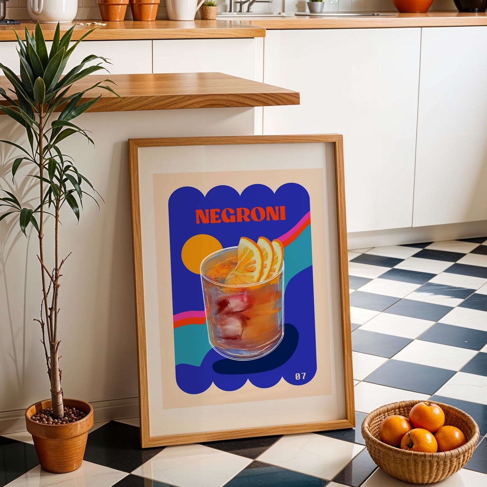 Framed Negroni cocktail poster on a checkered floor with a plant and bowl of oranges in a kitchen.
