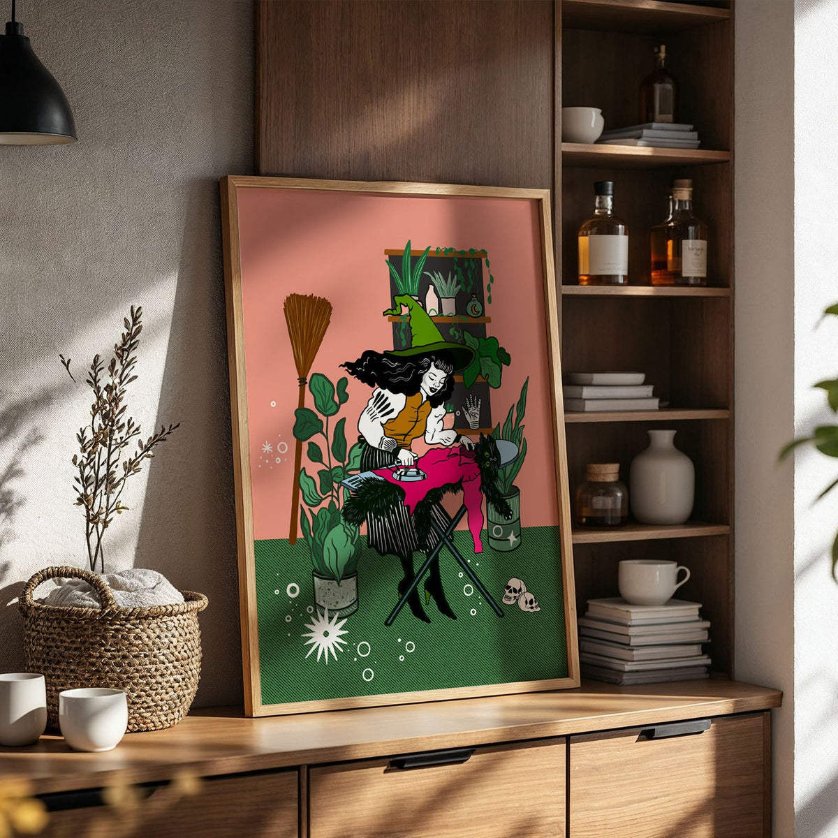 A whimsical and fun art print of a witch ironing her cat by mistake in the colour pink and green 